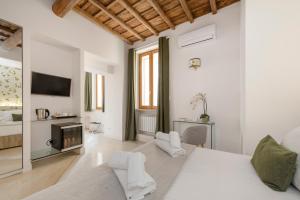 a white bedroom with a bed and a tv at i Fiori de' Mario Suites in Rome