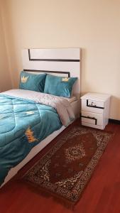 a bedroom with a bed with a blue comforter and a rug at Addis Joy Guesthouse in Addis Ababa