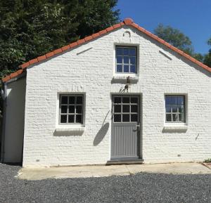 un edificio in mattoni bianchi con una porta e due finestre di Petite maison privative dans un environnement idyllique a Lasne