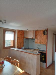 a kitchen with wooden cabinets and a table and chairs at Appartement saisonnier Orcières Merlette in Orcières