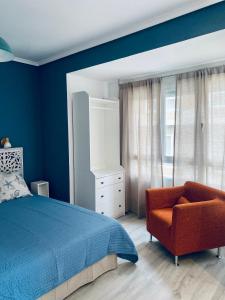 1 dormitorio con paredes azules, 1 cama y 1 silla en Casa La Ola Azul, en Alicante