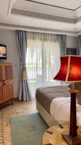 a bedroom with a bed and a large window at Pavillon du Golf -Palmeraie suites in Marrakech