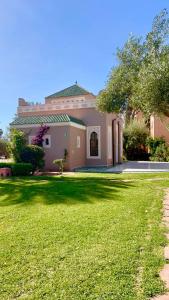 una casa grande con un césped verde delante de ella en Pavillon du Golf -Palmeraie suites, en Marrakech