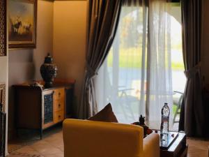 a living room with a yellow chair and a window at Pavillon du Golf -Palmeraie suites in Marrakech