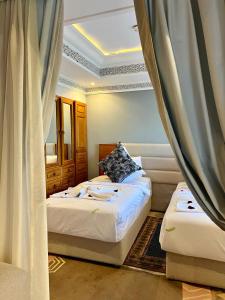 - une chambre avec 2 lits et une fenêtre avec des rideaux dans l'établissement Pavillon du Golf -Palmeraie suites, à Marrakech