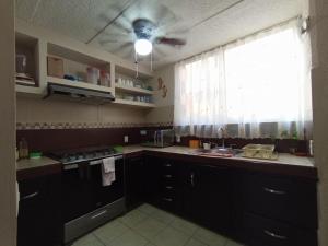 a kitchen with black cabinets and a ceiling fan at Casa Ixtlán Planta Baja in Santa Cruz Huatulco