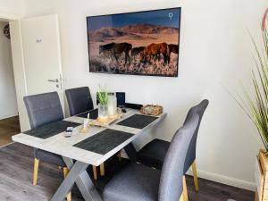 a dining room table with chairs and a painting on the wall at Christinas Fewo DÜNE 43 in Salzgitter Thiede in Salzgitter