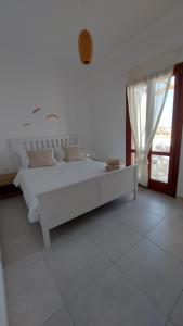 a white bedroom with a white bed and a window at Sea breeze houses in Monolithos +32 photos