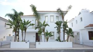 een wit huis met palmbomen ervoor bij Amalthea in Protaras