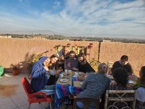 een groep mensen die rond een tafel zitten bij Hostel Afgo Rooftop in Ouarzazate