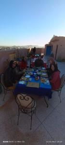 een groep mensen die rond een tafel eten bij Hostel Afgo Rooftop in Ouarzazate