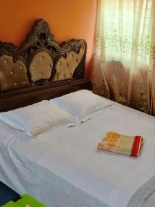 een wit bed met een sierlijk hoofdeinde en kussens bij Hotel Al-Hayat Abasik in Dhaka