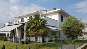 una casa blanca con una palmera delante de ella en Black and White B&B Urgnano, en Urgnano