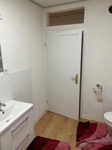 een badkamer met een wastafel, een toilet en een deur bij Ferienwohnung Kotsch in Engen