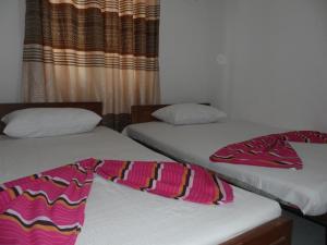 twee bedden in een hotelkamer met een deken erop bij D2 Holiday Inn in Badulla