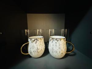 two white vases with gold handles sitting on a table at Blok in Sajmište