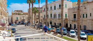 una calle de la ciudad con palmeras y coches aparcados en de Lucia Affittacamere - Elegante appartamento storico nel cuore della città, en Terlizzi