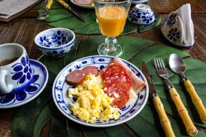 uma mesa com um prato de comida para o pequeno-almoço e um copo de sumo de laranja em Glamping Mangarito em Iporanga