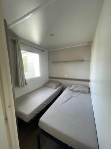 Duas camas num pequeno quarto com uma janela em Mobil Home de Marine em Port-la-Nouvelle