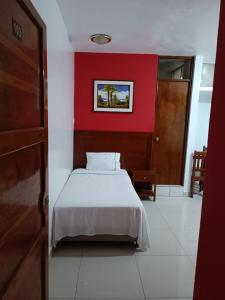 1 dormitorio con cama blanca y pared roja en Hotel ESPLENDOR, en Chiclayo