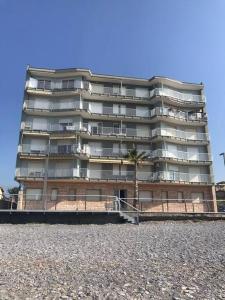 een hoog gebouw met een palmboom ervoor bij Appartamento sul mare (Ventimiglia/Bordighera) in Vallecrosia
