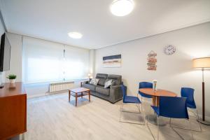 ein Wohnzimmer mit einem Sofa und einem Tisch in der Unterkunft Apartamentos GO - Génova Parquesol - Parking Gratuito in Valladolid