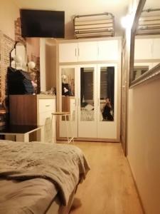 a room with a bed and a kitchen with white cabinets at Apartamenty na doby in Siedlce