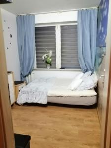 a bedroom with a bed and a window with blue curtains at Apartamenty na doby in Siedlce