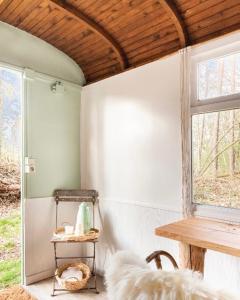 een woonkamer met een tafel en een raam bij Gehele accommodatie met boshuisje en 3 woonwagens in Ranst