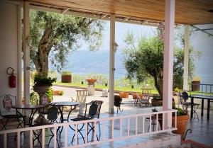 eine Veranda mit Tischen, Stühlen und einem Baum in der Unterkunft Villa Scilla e Cariddi in Messina