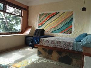 Cette chambre dispose d'un lit et d'une peinture murale. dans l'établissement Casa Musgo, à Xilitla