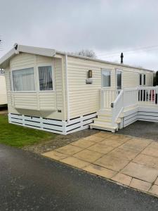 a mobile home with a porch and white railing at Olivia Ann in Caernarfon