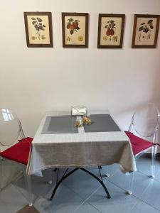 stół jadalny z 2 czerwonymi krzesłami i białą ścianą w obiekcie Casa Garruba Central Station w mieście Bari
