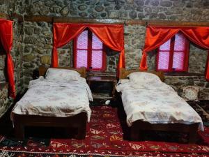 two beds in a room with red curtains and windows at Black Tower in Plav