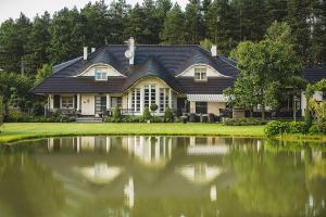 奥普尔Hubertus Dwór Myśliwski的前面有一个大池塘的房子