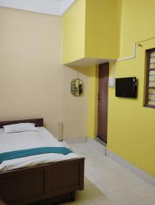 een slaapkamer met een bed en een gele muur bij RATHORE INN in Panchanai