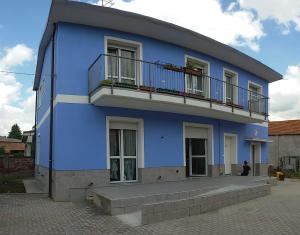 un edificio azul con un hombre sentado frente a él en B&B Honey Rooms, en Saronno