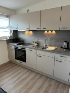 a kitchen with white cabinets and a sink at Ferienwohnung Wibi in Biedenkopf