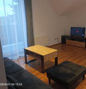 un salon avec une table en bois et une télévision dans l'établissement Apartamenty Jagiełło, à Zamość