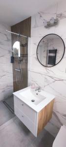 La salle de bains est pourvue d'un lavabo blanc et d'un miroir. dans l'établissement Apartamenty Jagiełło, à Zamość