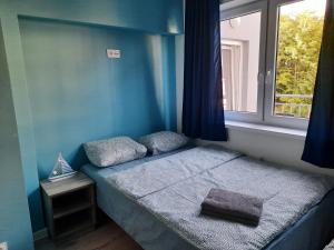 a small bed in a blue room with a window at Nadmorski Bursztyn - Dębina in Debina