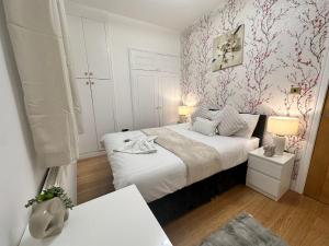 a small bedroom with a white bed and pink wallpaper at 2 Bedroom Apartment In Central London in London