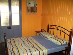 a bedroom with a bed with a striped blanket and a door at Mango tourist Hostel in Hervey Bay