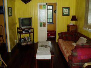 ein Wohnzimmer mit einem Sofa und einem TV in der Unterkunft Mango tourist Hostel in Hervey Bay