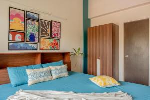 a bedroom with a blue bed with paintings on the wall at Bellini, Anjuna, Goa, 5 Mins from Beach, Centrally Located in Anjuna