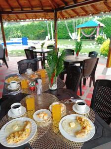 a table with plates of food and orange juice at Finca Hotel Amanecer del Cafeto in Montenegro