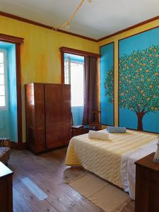 a bedroom with a bed and a painting of a tree at Avó da Rosa 2 in Faial da Terra