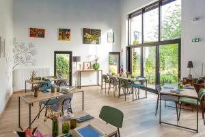 a room with tables and chairs and large windows at Aubépine in Sains-du-Nord
