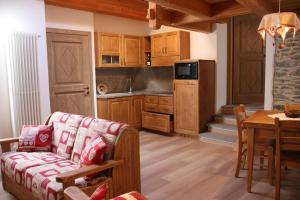 ein Wohnzimmer mit einem Sofa und einem Tisch sowie eine Küche in der Unterkunft Lo Trapei in Aosta