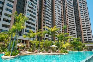 a pool with palm trees in front of tall buildings at Incrível resort paradisíaco! in Sao Paulo